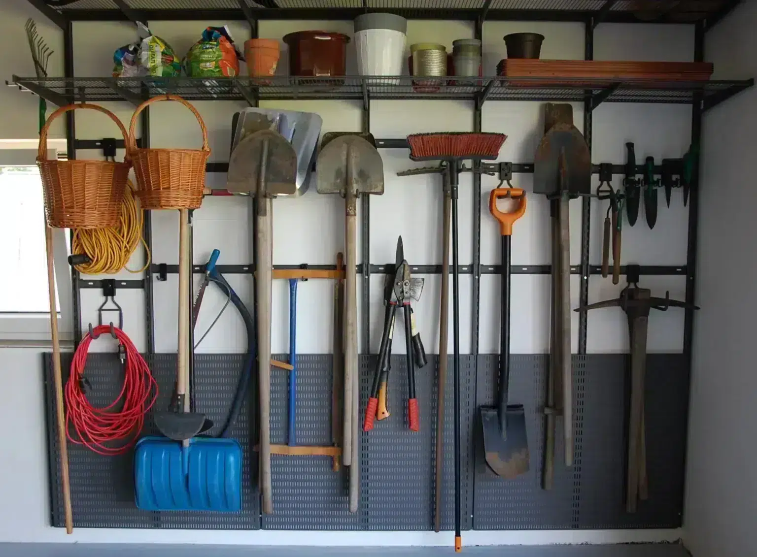 Řešení zavěšení zahradního nářadí úložným systémem Elfa v rámci řady Garage+.